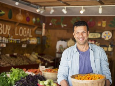 A farm growing and selling organic vegetables and fruit. A man holding a bowl of basket of freshly picked tomatoes.