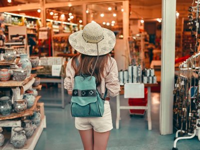 Young cute girl tourist in a blouse, a straw hat and shorts with a backpack walks around the city ethnic market. Travel, tourism concept.